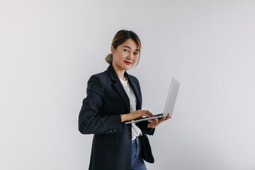 Happy asian Thai business woman wear blazer holding laptop, smiling and looking at camera, typing keyboard notebook, isolated over white background wall.