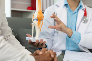 Male doctor and male patient discussing knee joint model It is likely that the focus will be on the condition of arthritis in the knee during a medical consultation at a hospital or clinic. medical he