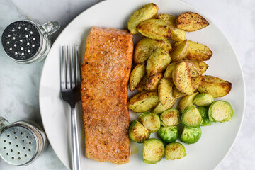 seasoned baked salmon  with potato wedges and roasted brussel sprouts,