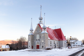 Sunrise winter view of 1749 fieldstone Sainte-Famille Church in the Island of Orleans, Quebec,...