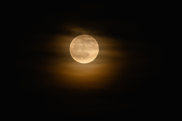 A bright full moon covered with soft clouds.