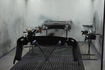 The photograph captures the scene of an automotive workshop, showcasing the process of painting...