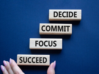 Decide Commit Focus Succeed symbol. Concept words Decide Commit Focus Succeed on wooden blocks. Businessman hand. Beautiful deep blue background. Business concept. Copy space.