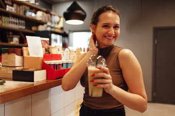 Happy young white girl drinking green smoothies in a stylish cafe indoor.