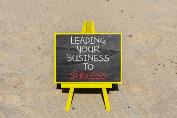 Leading your business to success symbol. Concept words Leading your business to success on beautiful blackboard. Beautiful sand beach background. Leading your business to success concept. Copy space
