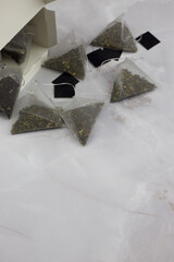 Tea pyramids with tea leaves and fruit flavor lie on a white table, vertical photo