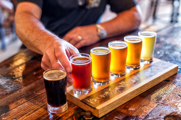 Mans hands reach in to try a flight of beers in a brewery