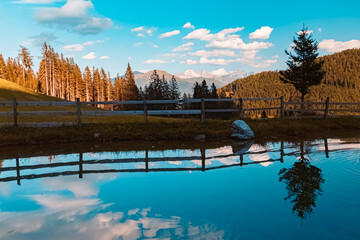 Alpine sunset or sundowner with reflections in a pond at the famous Maria Waldrast monastery,...