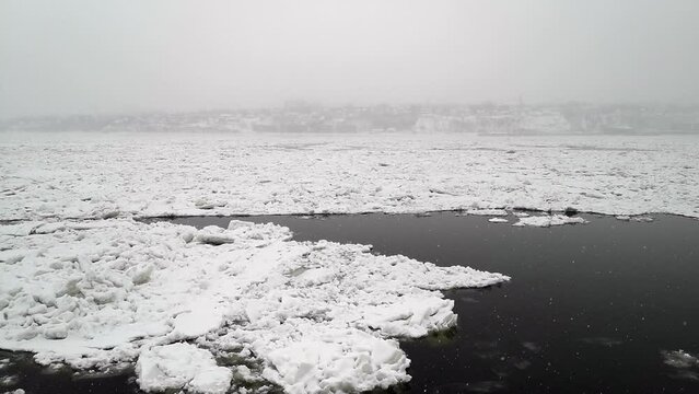 Under the snow, ice floating on the St Lawrence river in front of a Quebec harbor dock, near the old Quebec City, with Levis in background (Quebec City, Quebec, Canada)