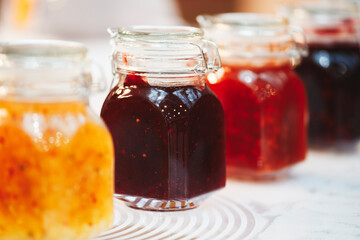 Glass jars with grain, nuts, butter, jam on the wooden shelf  on background of a dark wall, breakfast concept, kitchen background, healthy eating concept, conservation concept