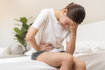 Obraz na płótnie Canvas Flatulence ulcer, asian young woman, girl hands in belly, stomachache from food poisoning, abdominal pain and digestive problem, gastritis or diarrhoea. Abdomen inflammation, menstrual period people.