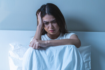 Naklejka premium Stressed can not sleep asian young woman, girl sitting on bed in bedroom at home, suffering from insomnia, awake at night in bedroom, tired. Frustrated with problem, exhausted on nightmares.