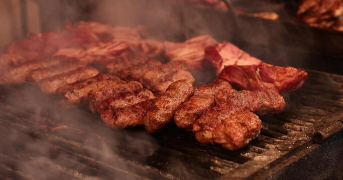 4k video of traditional romanian food Meat Balls "mici" on the grill with smoke and flames.