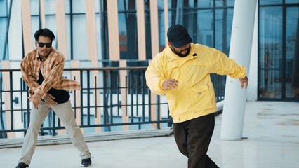Hipster perform break dancing while partner dancing together at corridor, modern mall. Hip-hop...