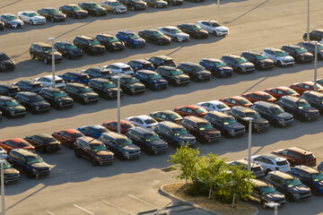 Large parking lot of local dealer with many brand new cars parked for sale. Development of american...