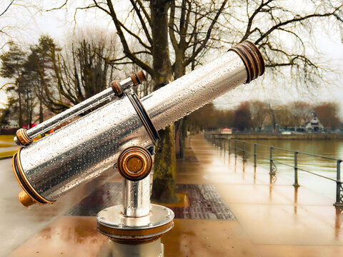 A telescope covered with raindrops, in the background the lake promenade of Bregenz on Lake Constance, Austria