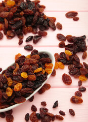 Raisins in white plate on pink wooden background. Vertical photo