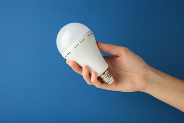 Light bulb in hand on blue background. Space for text
