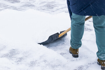 an unrecognizable man cleans snow with a shovel in a snowfall. close-up © Anton Vakhrushev