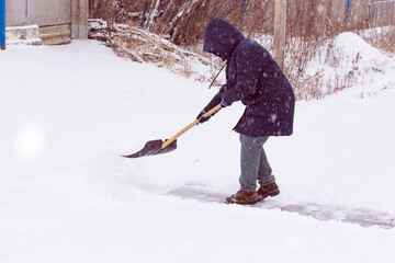 Naklejka premium an unrecognizable man cleans snow with a shovel in a snowfall. close-up