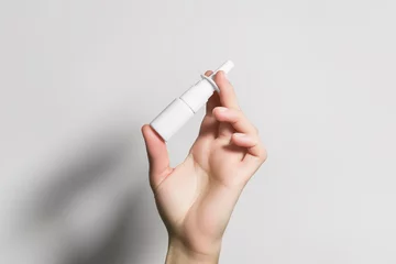 Foto op Aluminium hand holding a white bottle with nasal spray © Iryna_B