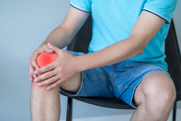 Knee pain, man suffering from ache and doing self-massage at home