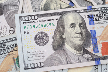 Close up of an American hundred dollar bill in a pile, Benjamin Franklin portrait focus. 