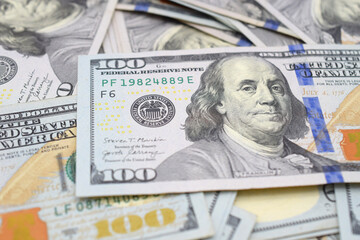 Close up of an American hundred dollar bill in a pile of money.