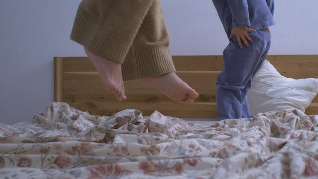 Children bouncing in bed in super slow motion captured with a high speed camera at 800 fps. Young brother and sister bonding while jumping up and down in the air