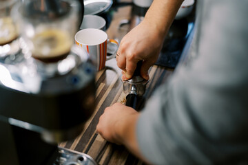 Barista tamping ground coffee in a portafilter with a tamper