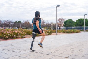 Jogger with prosthetic leg running along an urban park