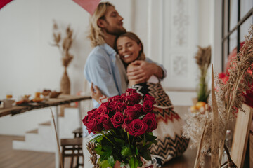 Young romantic couple embracing while celebrating love anniversary at the decorated home