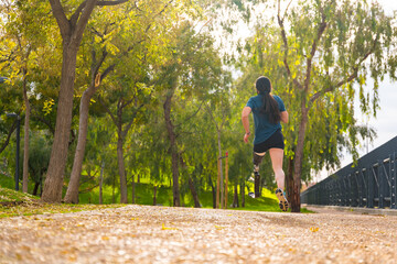 Obraz premium Athlete with prosthetic leg running along a park