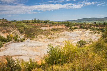 Old closed quarry. Puddles in an old quarry. Trees growing over geological structures of hercynian orogeny inside of old closed quarry in mountains in Ukraine