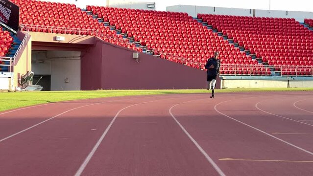 Asian para-athlete with prosthetic blades leg in stadium practicing workout for Paralympic running competition. Amputee sportsman runner practicing running workout. Disabled athlete man sport concept.