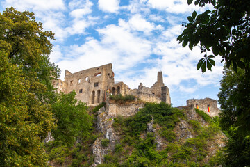 Beckov Castle, standing on a high cliff, surrounded by greenery.
