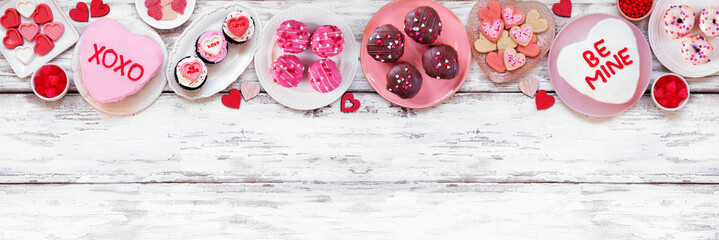 Valentines Day top border with assortment of fun desserts and sweets. Overhead view on a white wood banner background. Love and hearts theme. Copy space. - Powered by Adobe