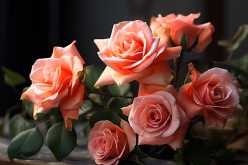  a bunch of pink roses sitting on top of a wooden table next to a vase with flowers inside of it and green leaves on the side of the top of the table.