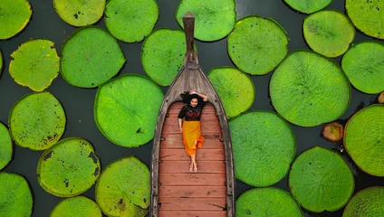 Fototapeten Aerial view of an Asian woman relaxing on a boat outdoor on Lotus pond at Phuket Thailand © shawlin