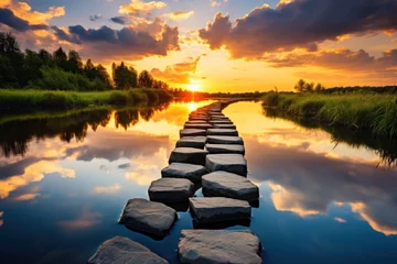  the sun is setting over a body of water with rocks in the foreground and a line of stepping stones in the middle of the water in the foreground. © Shanti