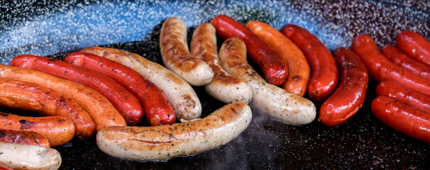 ..Cooking different types of sausages on the grill. Delicious sausages close-up. Banner