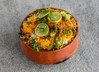 Spicy chilman, matka or clay chicken biryani pot topping with lime slice and oriander served in...