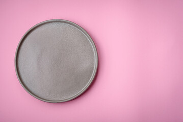 Empty round ceramic plate on a plain background, flatley with copy space