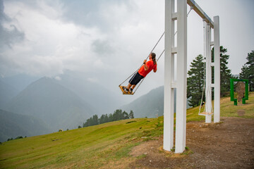Orange T-Shirt Momentum: Man Experiencing Weightless Joy on the Swing
