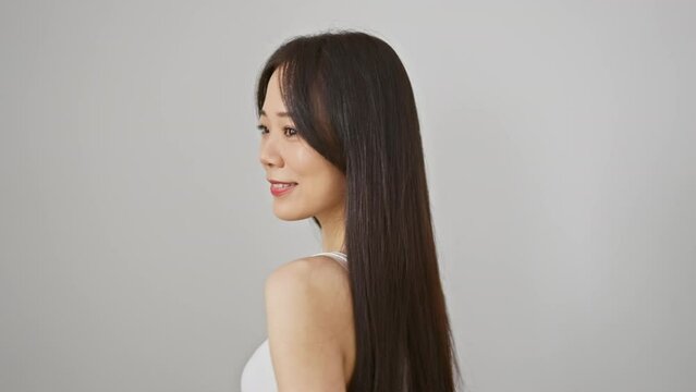 Young asian woman in white tank top smiling against isolated white background