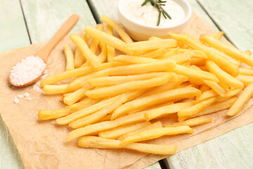 Tasty french fries, mayonnaise and salt on green wooden background