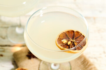 Glass of tasty martini and dry lemon on white wooden table