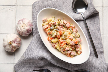 Bowl of tasty Olivier salad on white tile background