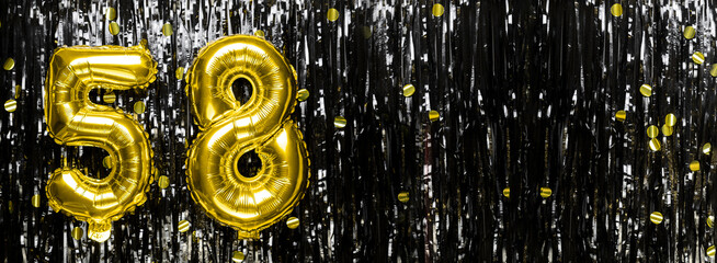 Gold foil balloon number number 58 on a background of black tinsel decoration. Birthday card,...
