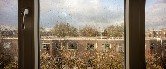 Window pane full of rain drops looking out over residential neighbourhood in Utrecht, The...
